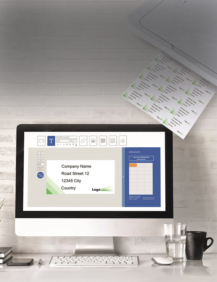 Ein Computerbildschirm zeigt ein Layout für eine Unternehmensvorlage mit Platz für Namen, Adresse und Logo. Ein Drucker gibt Etiketten aus.
